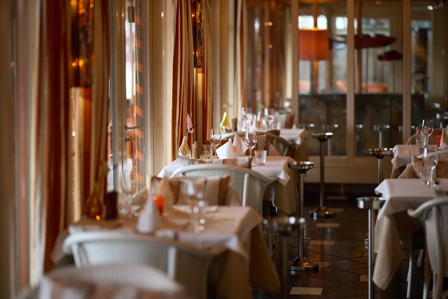 Zaal met wit gedekte tafels langs de ramen